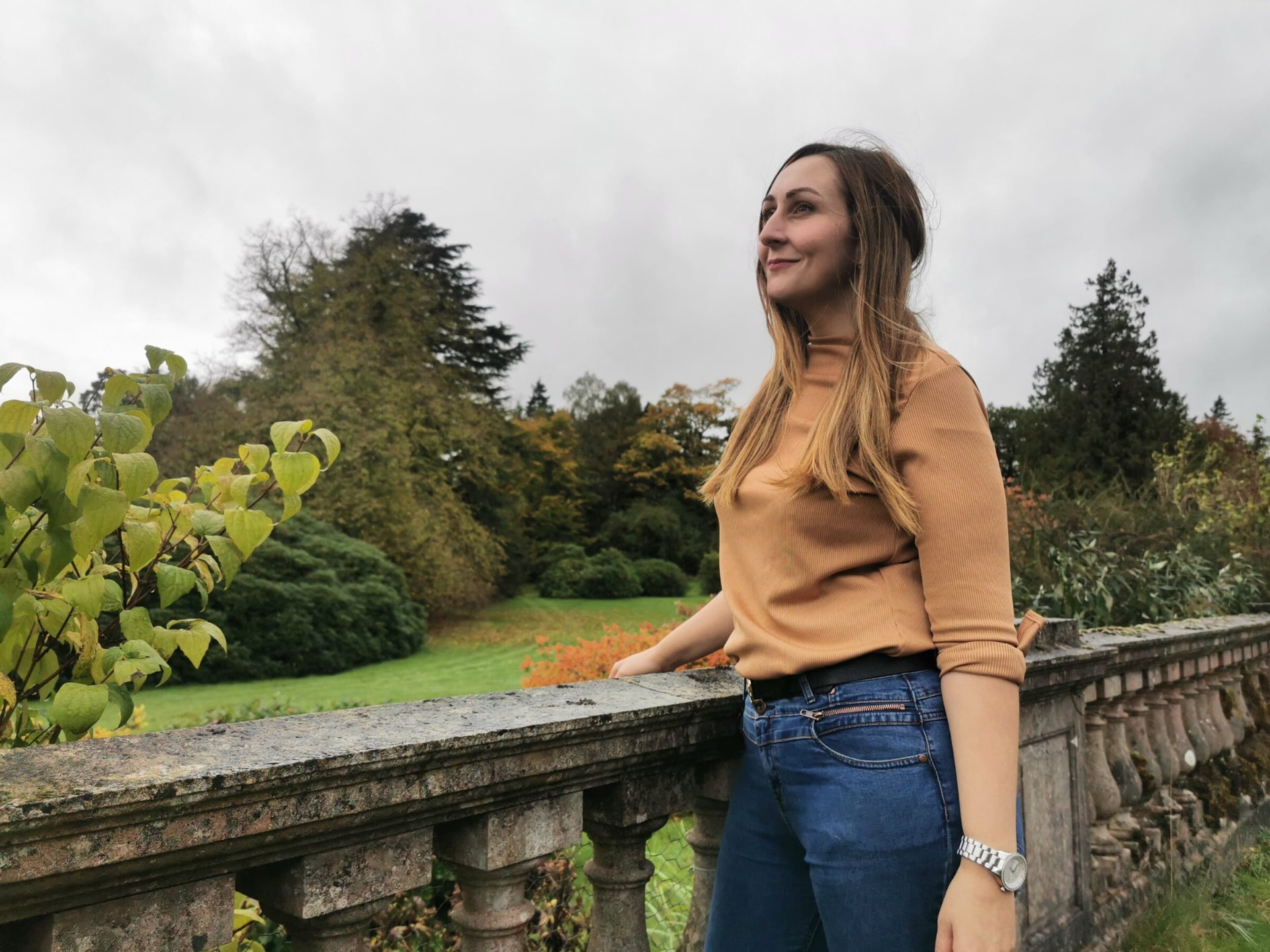 Katie Ford on a stone terrace, looking out over the trees