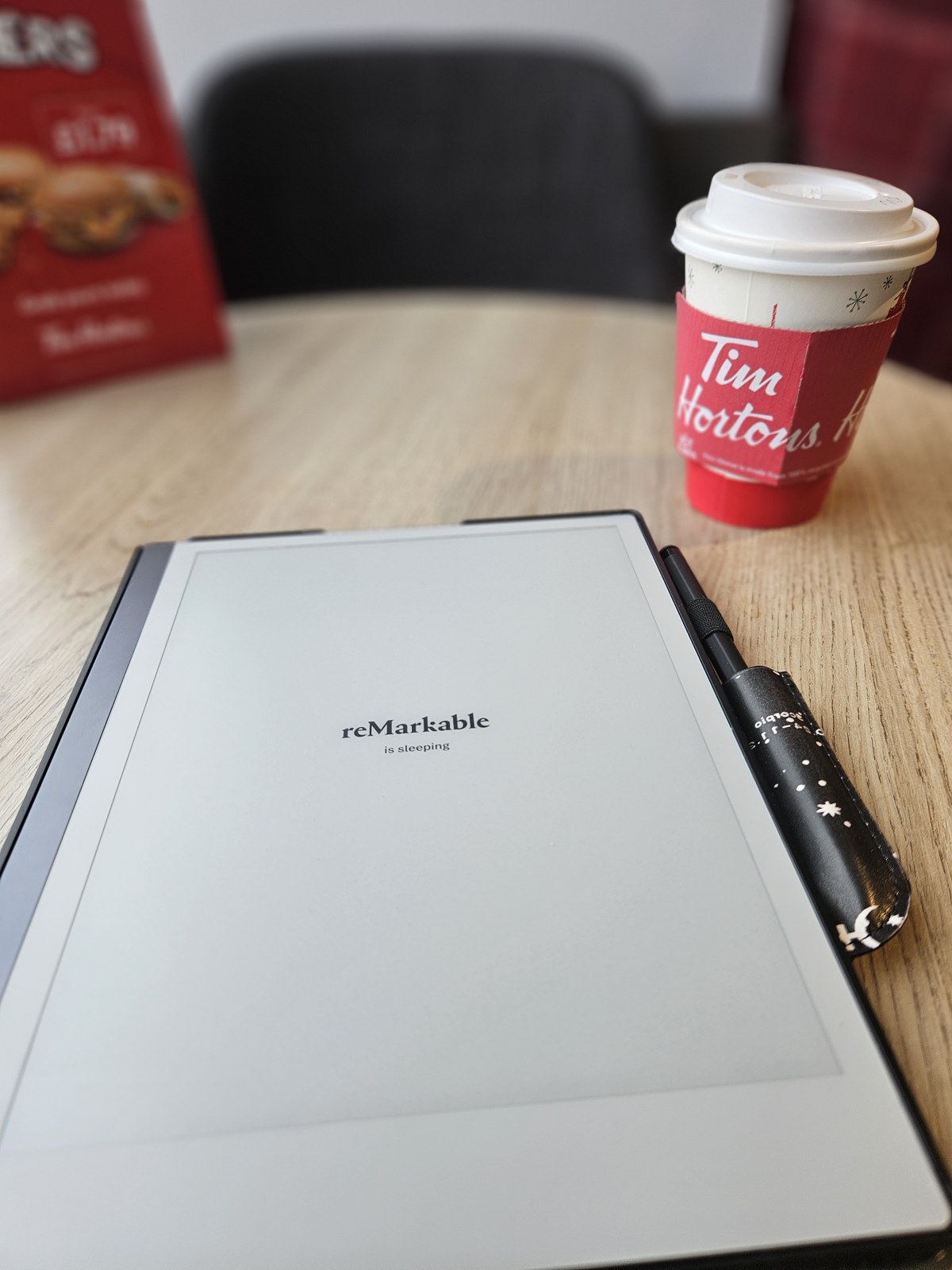A digital notepad and pen beside a takeaway coffee