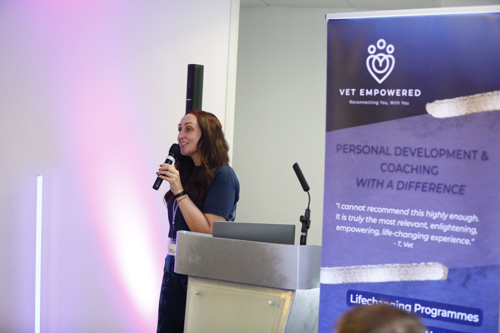 Katie Ford speaking at a podium beside a Vet Empowered banner